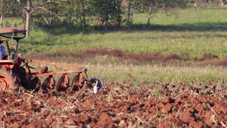 agricultural tractor tilling soil in a rural landscape.