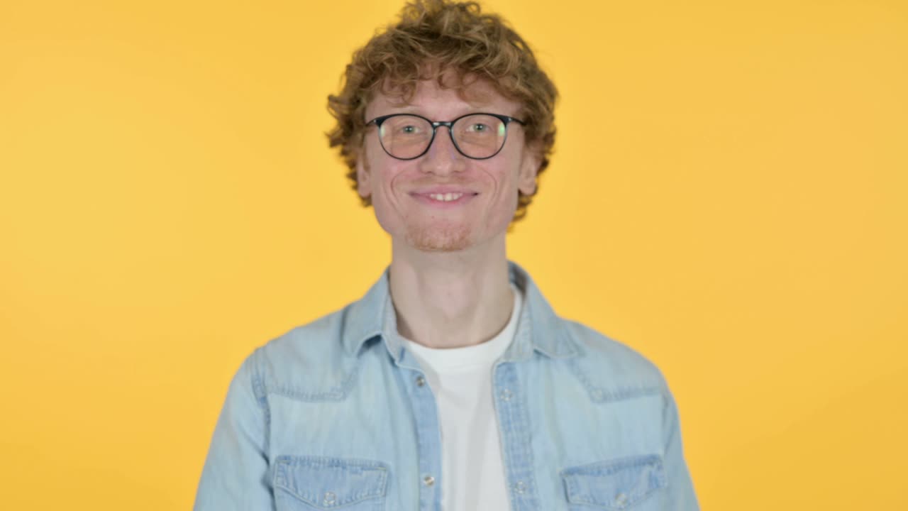 joven pelirrojo riéndose de una broma, fondo amarillo