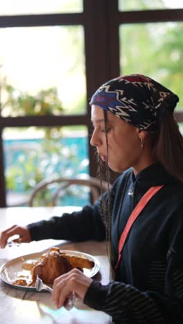 woman enjoying breakfast croissant in a cafe