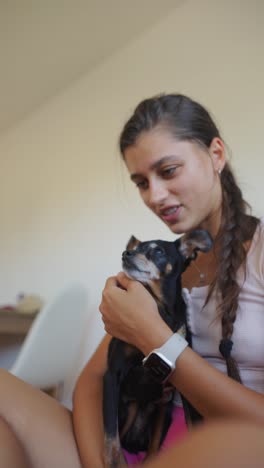 a young woman cuddling and interacting with her small dog, capturing a yawn