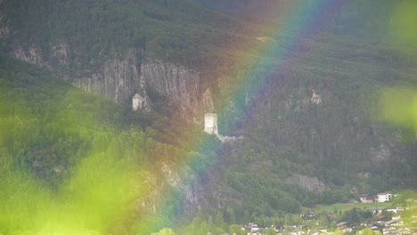 arco iris frente a la ruina del antiguo castillo y un bosque con un pueblo al fondo en tirol, austria