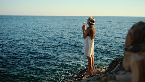 woman taking picture of ocean from cliff