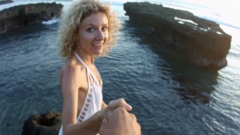 man following cheerful woman on beach