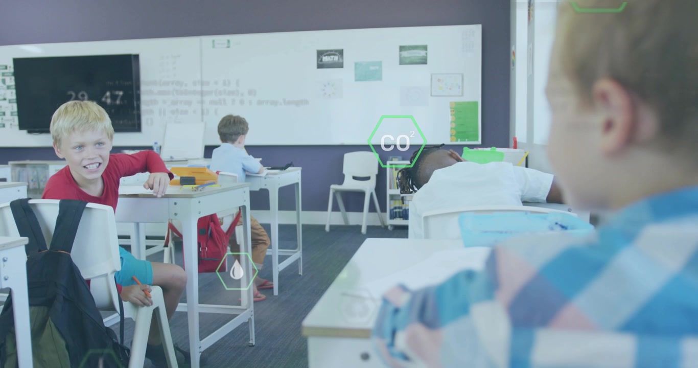 チェック柄のシャツを着た少年が学校で書き物をしていると、浮遊する六角形のアイコンが現れ、友人が笑顔で振り返る。
