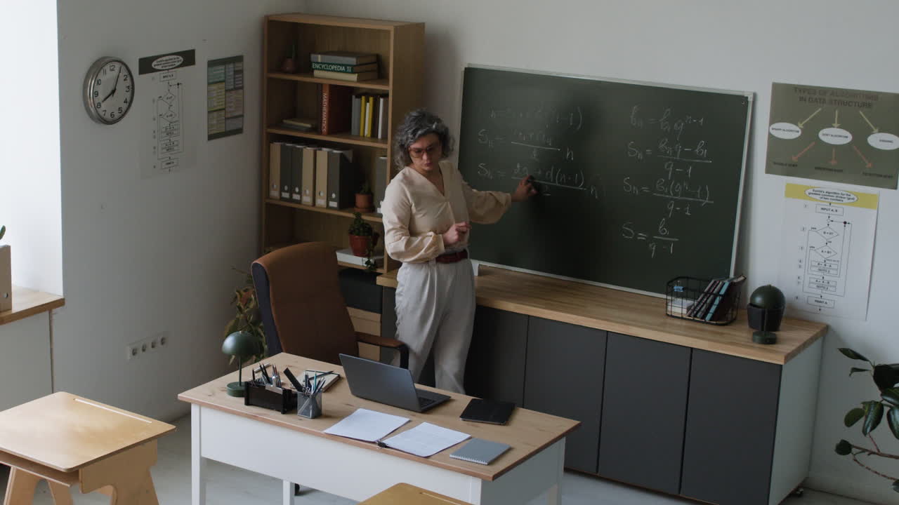 Teacher explaining math concepts on a blackboard in a classroom