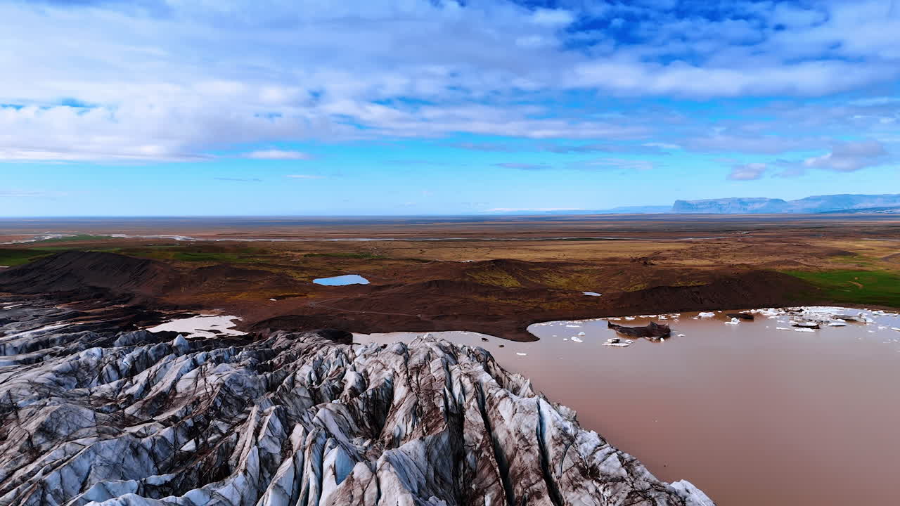 Ancient glaciers, lake with brown water and rocky landscape with no vegetation. Stunning scenery of Iceland from drone.