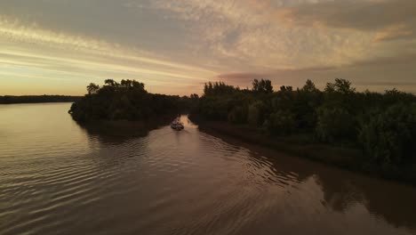 aerial drone shot of ship carrying small boat on amazon river during beautiful sunset