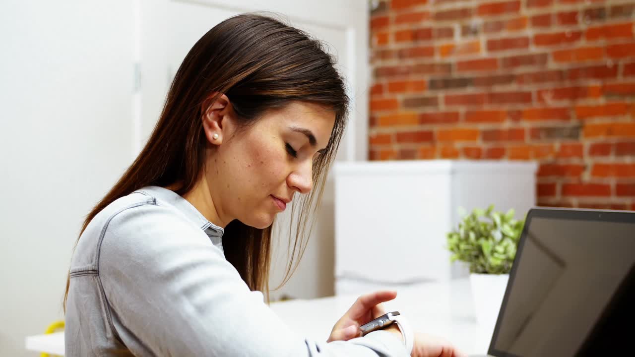 mujer ejecutiva usando un reloj inteligente en el escritorio