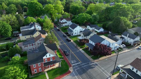 quiet american housing area with two-story homes and porch in american district. sunny day with lush greenery in spring. aerial approaching shot. modern solar panel units on rooftop.