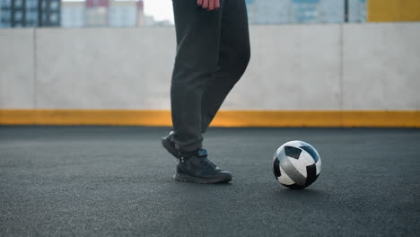 side leg view of sportsman demonstrating precise ankle twists with left and right leg, skillfully controlling soccer ball in sport arena featuring goalpost and painted wall