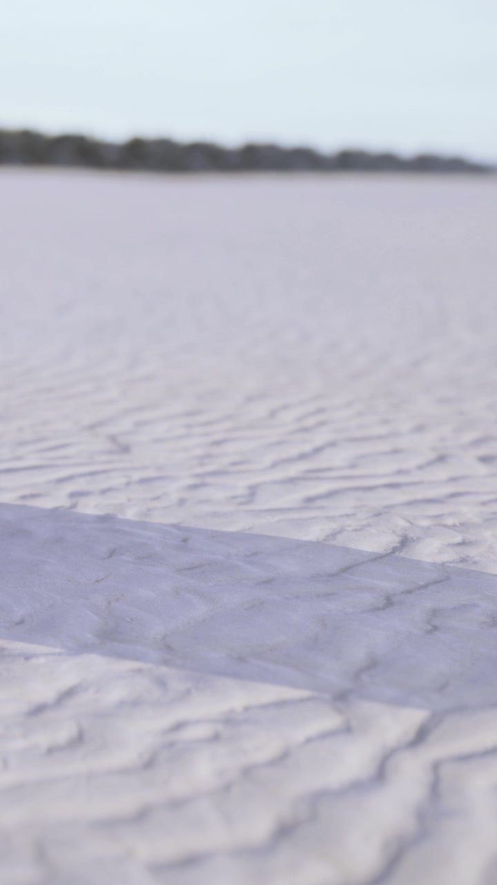 Sand patterns form on a beach by the ocean during daylight hours
