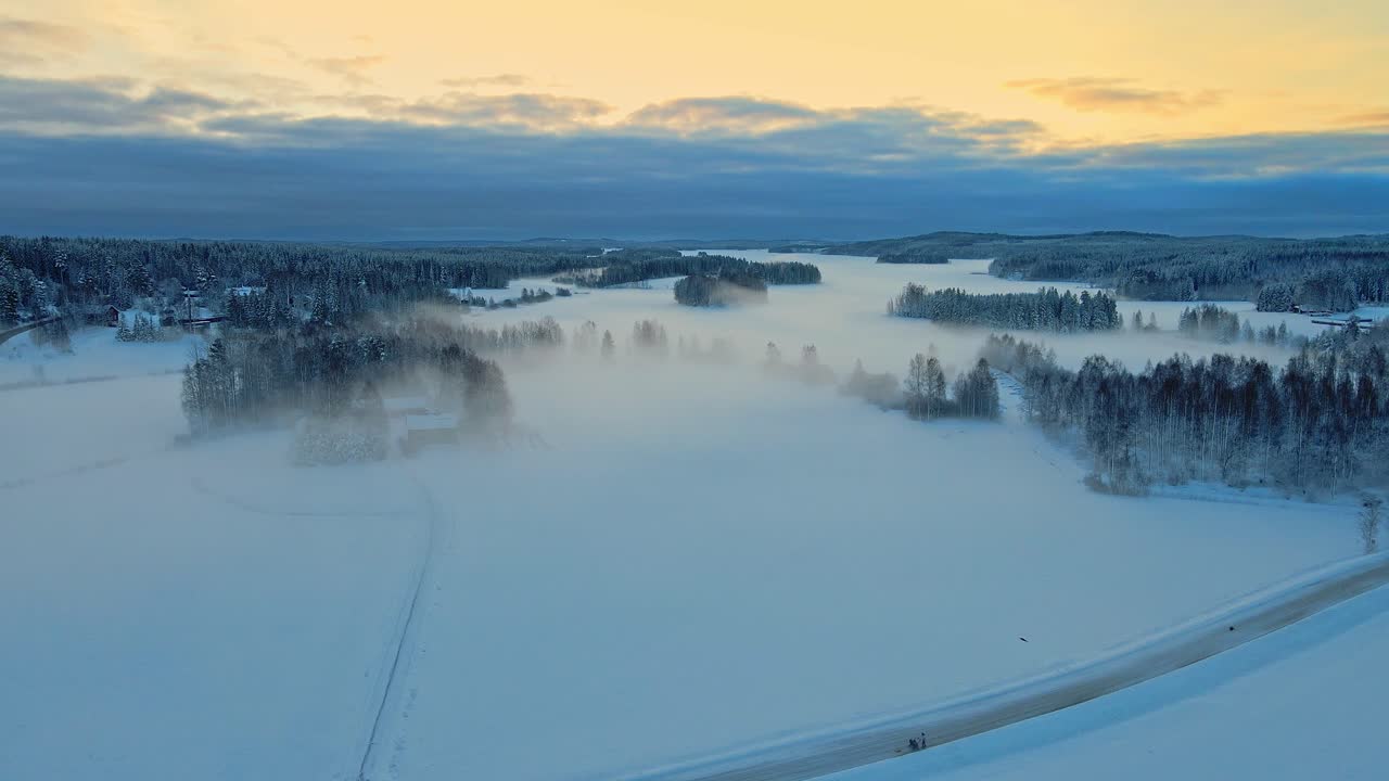 Tåkete, snødekte jorder og skog ved en vakker soloppgang en vintermorgen