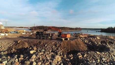 slow orbiting aerial shot of an excavator digging and loading dirt into a truck
