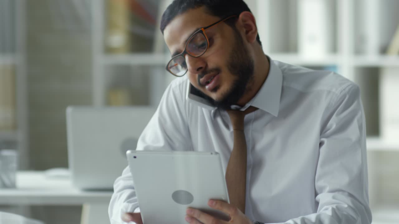 gerente de oriente medio usando tableta y hablando por teléfono en la oficina