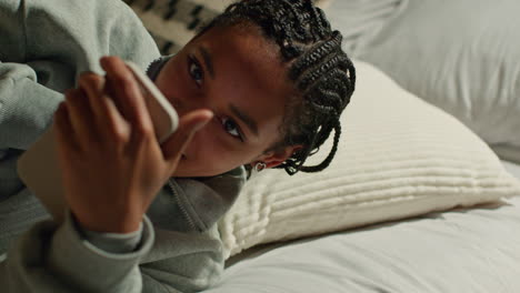 adolescente usando el teléfono inteligente en la cama