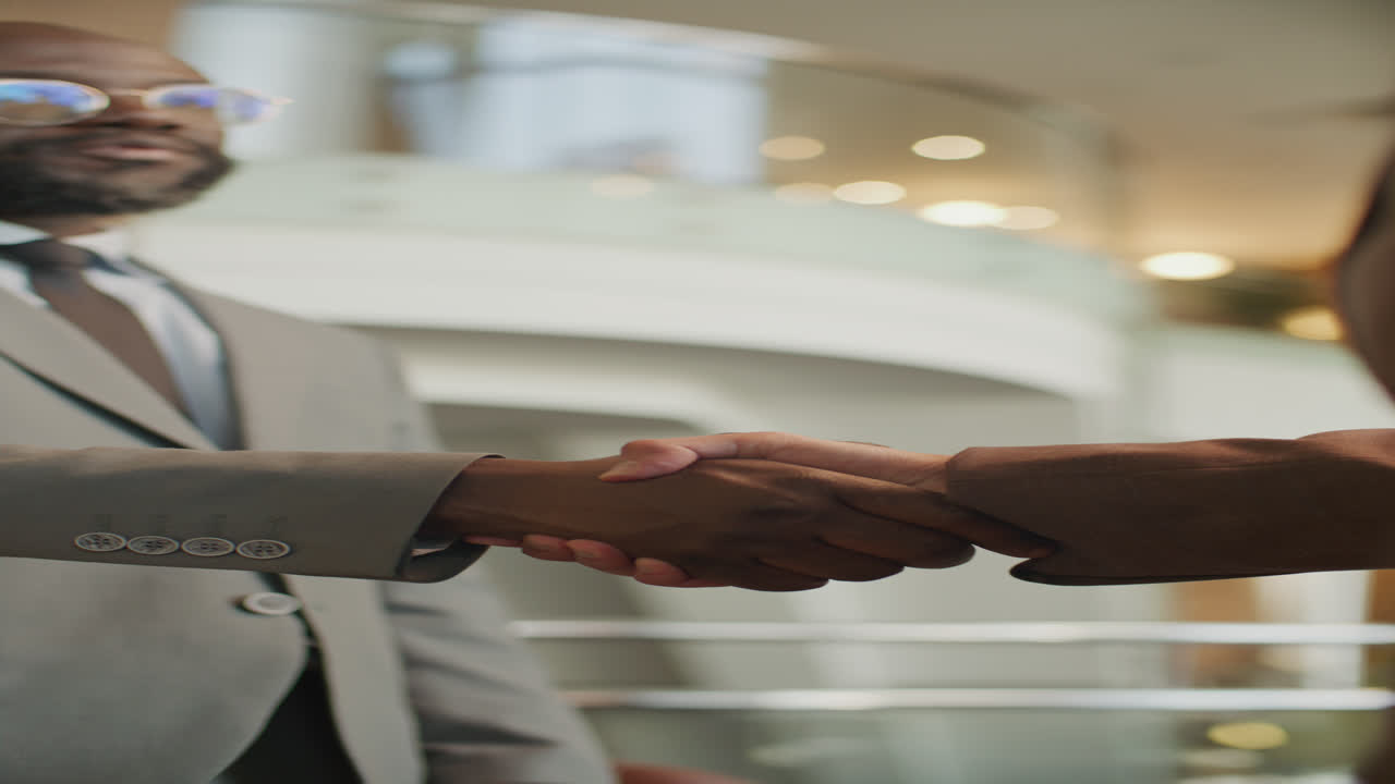 Vertical of Two Businessmen Shaking Hands and Talking in Hotel Lobby
