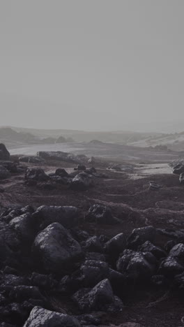 a rocky and desolate landscape with fog in the distance