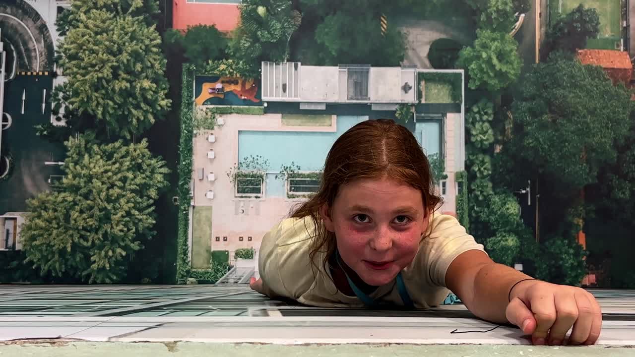Optical illusion of little girl clinging to wall of building pretending not to fall