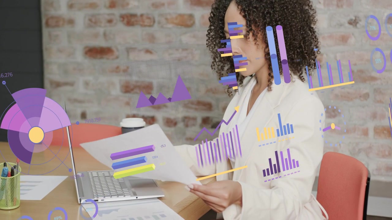 Female analyst typing on laptop, starting business charts around her while checking printed reports