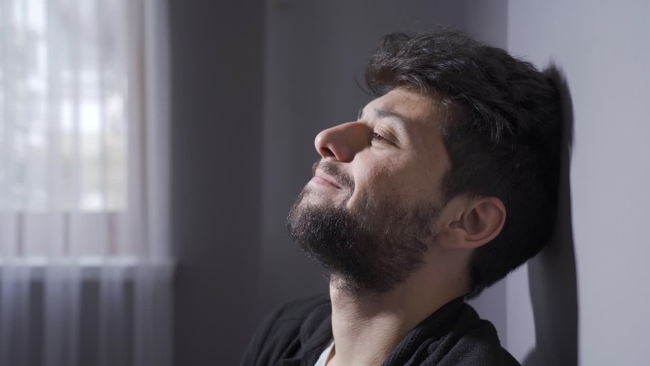 un hombre con enfermedad mental está sentado junto a la pared en su casa.