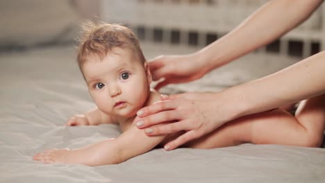 close-up side view of mother's hands rubbing baby's back