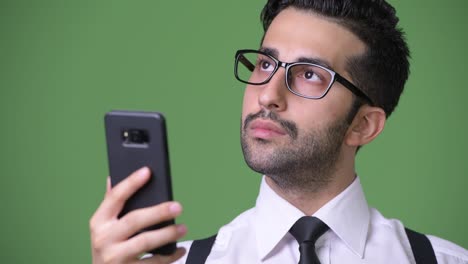 young handsome bearded persian businessman against green background