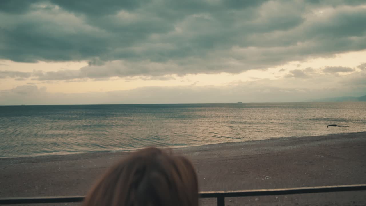 mujer sentada en un banco y mirando la playa con vistas al mar