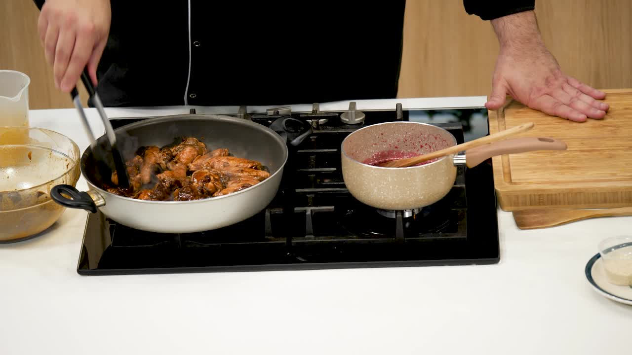 A chef prepares delicious chicken on the stovetop while a vibrant sauce simmers in a pot. The kitchen features a clean, contemporary design and well-organized tools