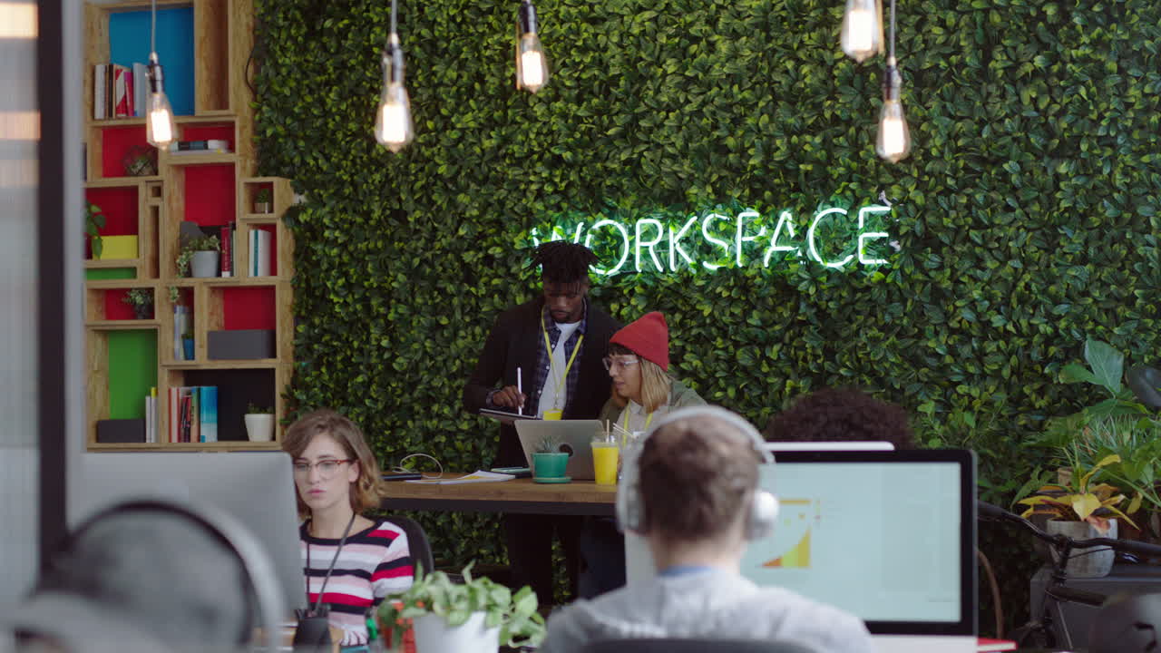 스타트업 사무실에서 일하는 창의적인 사업가 아프리카계 미국인 팀 리더 남자가 컴퓨터 화면을 가리켜 아이디어를 보여주고 훈련 인턴 피드백을 공유하고 브레인스토밍을 하며 정보를 논의합니다.