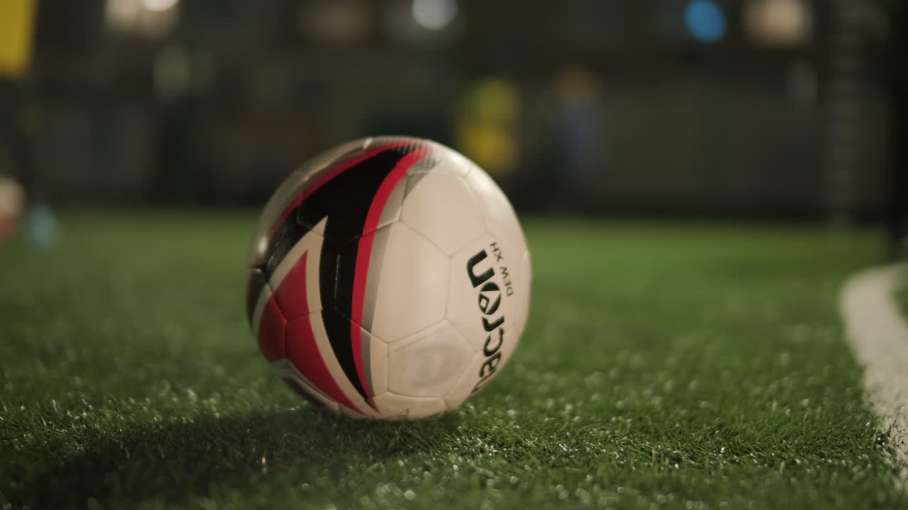 Et børnefodboldhold træner på stadion under vejledning af en træner. Børn i sportstøj øver boldøvelser, forbedrer teknik og udvikler teamwork på den grønne bane