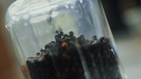 una foto de cerca de las semillas de especias secas aromáticas llenándose en un frasco de vidrio