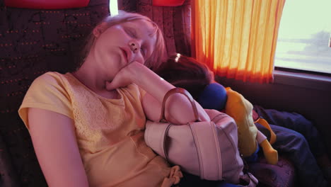 Zwei-Kleine-Müde-Mädchen-Schlafen-Auf-Rucksäcken-In-Einem-Touristenbus