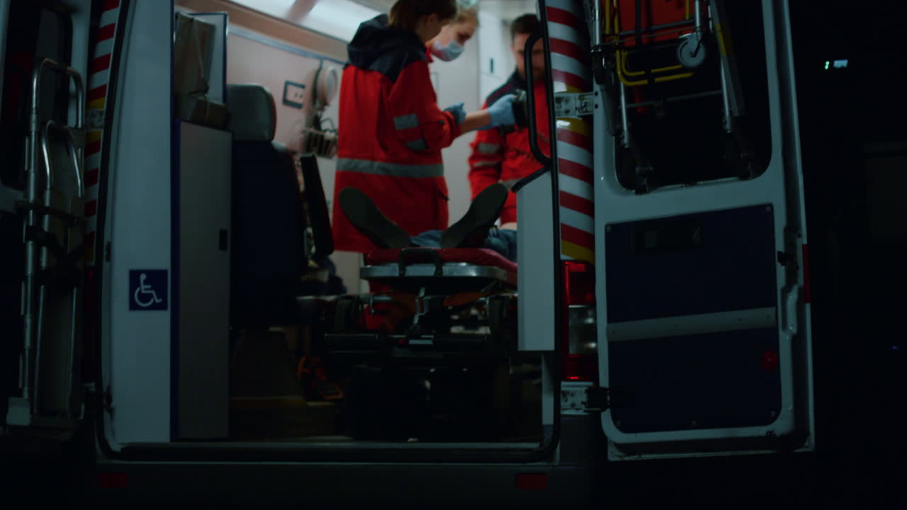 응급 의사 들 이 구급차 에서 디피브릴레이터 를 장착 한 환자 를 소생 시키고 있다