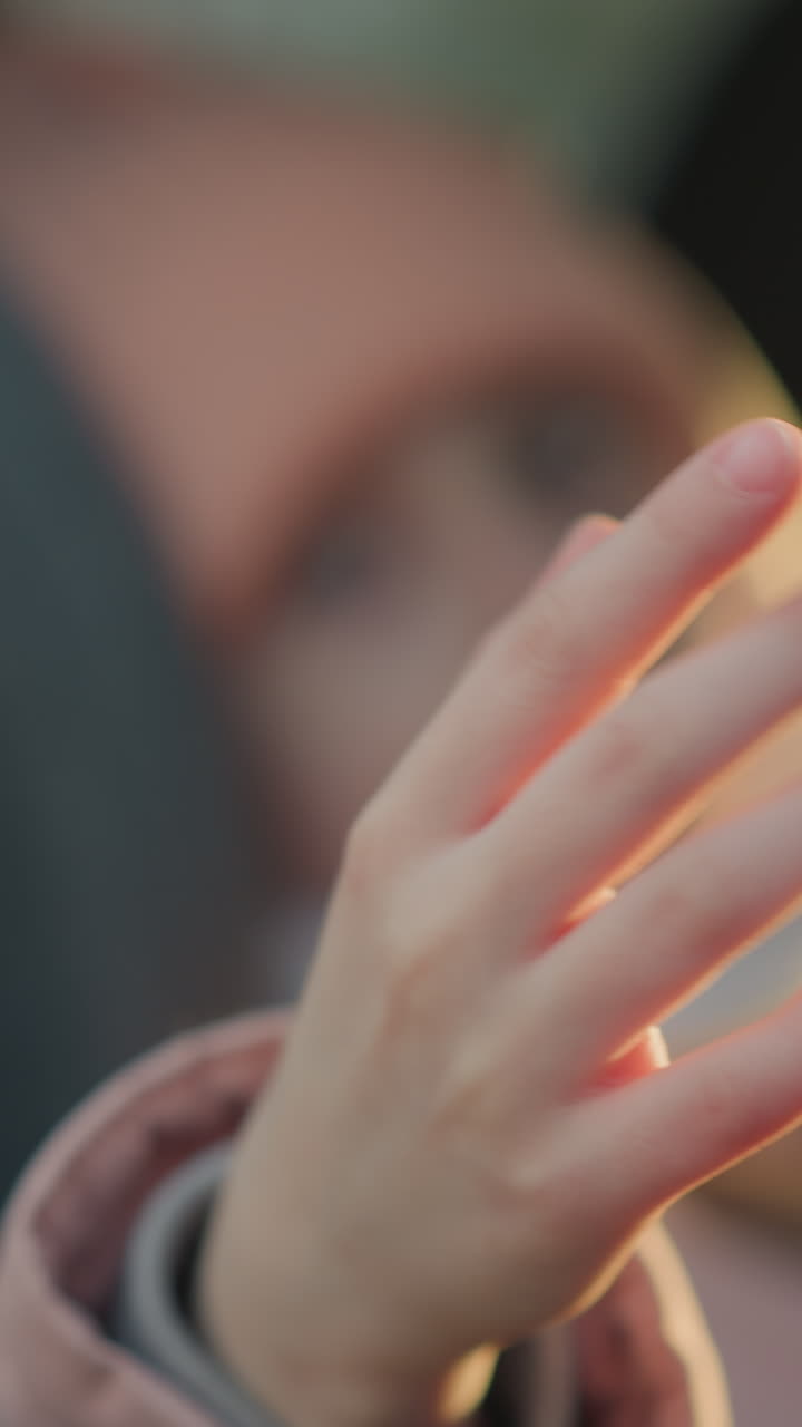 핑크색 재을 입은 어린 소녀가 손을 흔들고 있는 근접, 약간 초점 밖의 시선, 흐릿한 효과는 부드럽고 따뜻한 빛과 부드러운, 평화로운 분위기를 강조합니다.