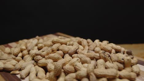 Spinning-wide-angle-of-a-pile-of-peanuts-on-a-cutting-board-with-a-black-background