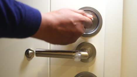 persona abriendo una puerta con un mango de metal y una cerradura