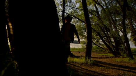 silhouette of a person playing guitar at sunset by the river