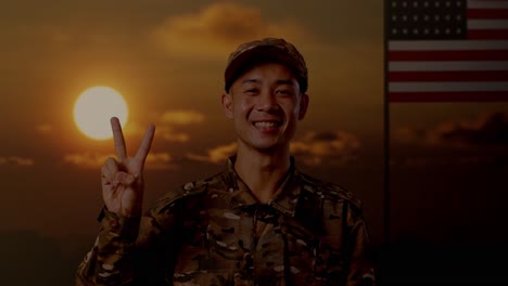 close up of asian man soldier smiling and showing peace gesture to camera while standing with flag of the united states, sunset time