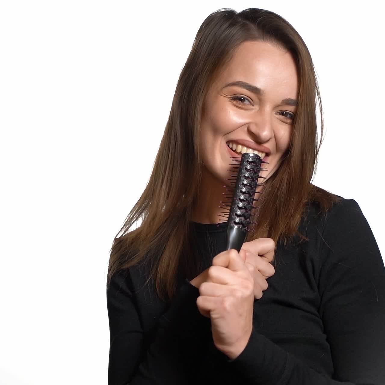 Girl combing brushing her hair by using comb. Beautiful young woman combing her healthy and shiny hair, studio white