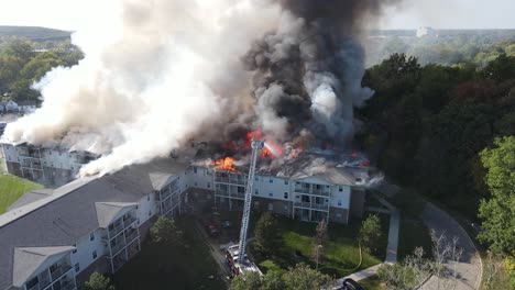 Burning-rooftop-of-senior-living-apartments-in-Michigan,-firefighters-arrived,-aerial-view