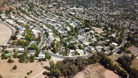 aerial approaching shot of american suburb neighborhood in california. road and streets in housing area with noble homes. drone flyover.