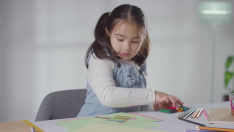 Shot-Of-Young-Girl-At-Table-At-Home-Drawing-And-Colouring-In-Picture-1