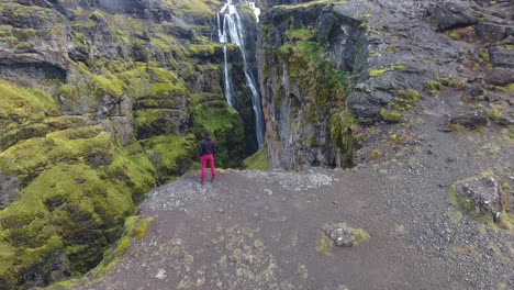 vista de un avión no tripulado volando sobre un hombre de pie en el borde de un cañón en islandia.