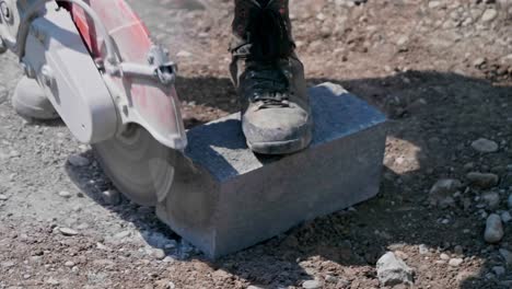 petrol cut off saw being used to trim stone block outside on the ground