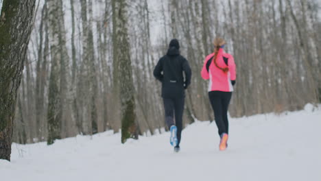 A-man-and-a-woman-run-in-the-park-in-winter,-practicing-a-healthy-lifestyle-and-socializing-with-their-health-in-the-park.