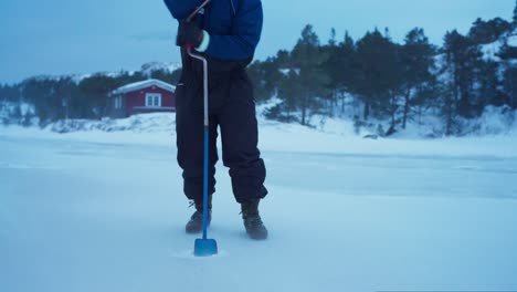 man making a hole in an iced lake for fishing - close up