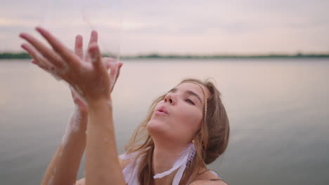 a young female artist shows a soap bubble show by blowing up large soap bubbles with her hands in slow motion