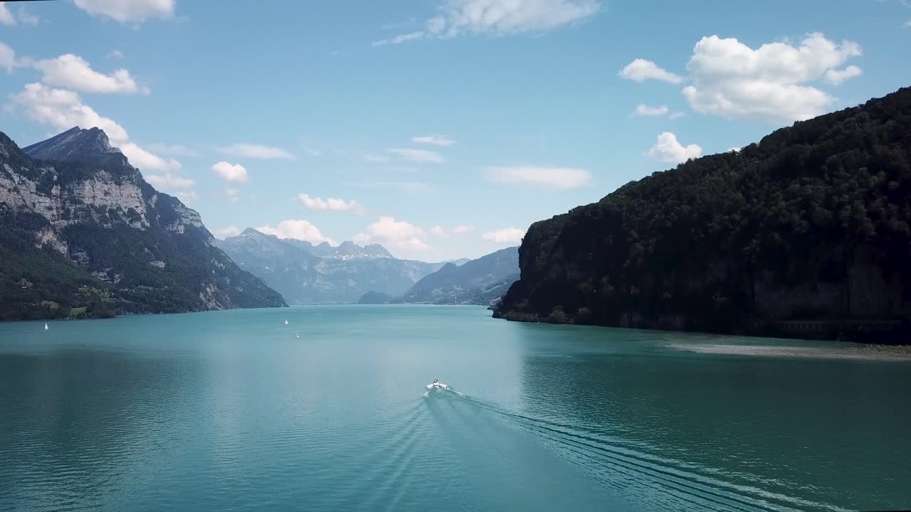 drone, toma aérea de un wakeboarder detrás de una lancha motora en un hermoso paisaje de lago de montaña en suiza