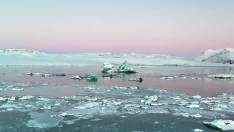 Gebrochenes-Eis-Und-Eisberge-Im-Jokulsarlon-Gletschersee-Mit-Rosa-Himmel-Bei-Sonnenaufgang-In-Island