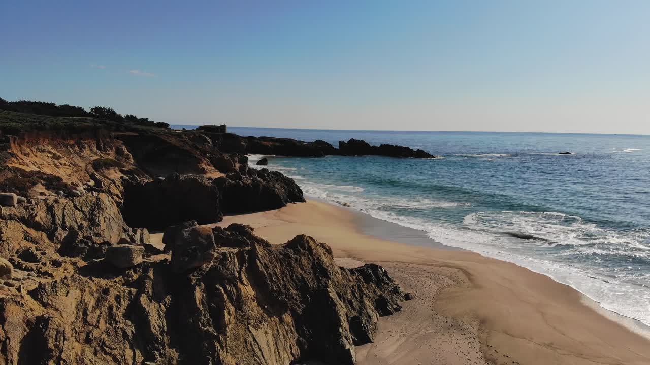 Ondas quebrando em uma praia costeira rochosa e ensolarada no final da tarde, pôr do sol na hora dourada